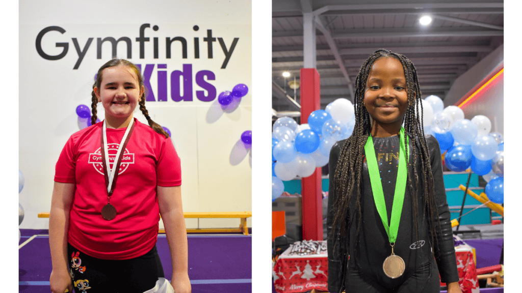Gymfinity Kids cheerleader girl with bronze medal at cheerleading competition, smiling in red sportswear in gym setting.