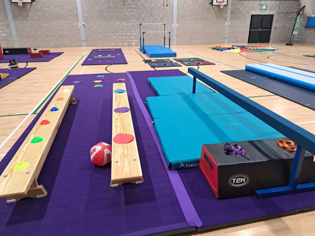 Climbing toys and mats set up inside a gymnasium on purple mats with various obstacle equipment for children's physical activities.