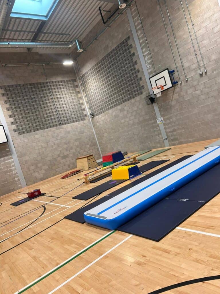 Rebound therapy equipment set up in an indoor gym for balance and coordination training; includes a large inflatable rebound surface, mats, and various training aids.