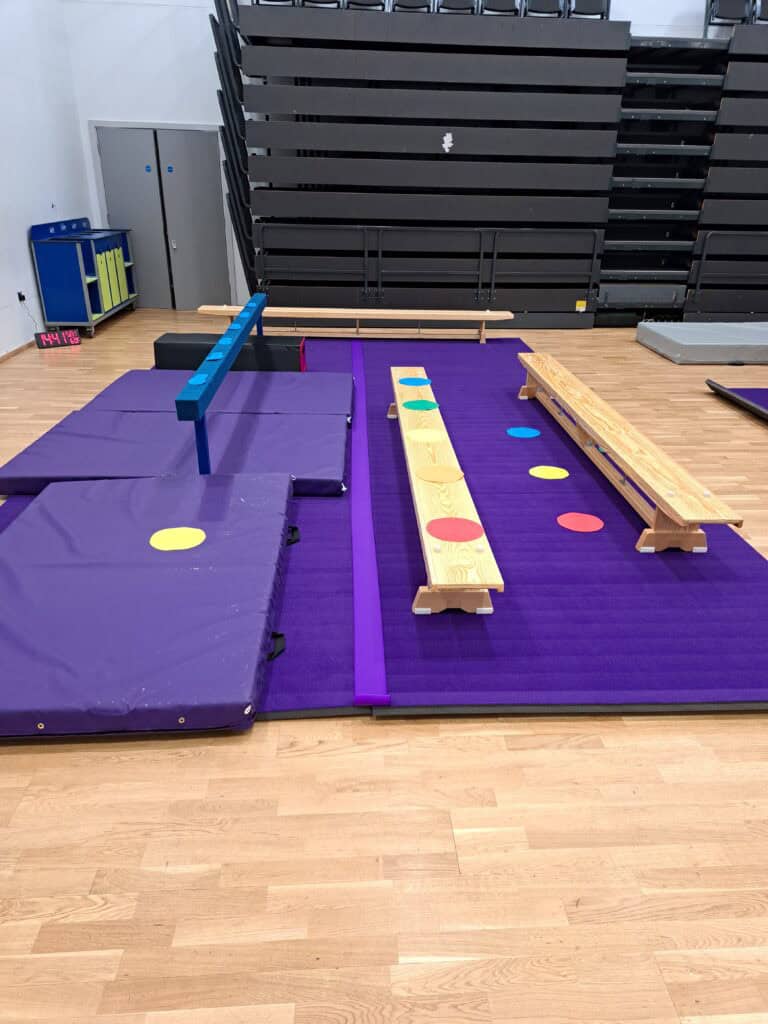 Climbing and agility training setup with padded mats, colourful obstacles, and balance beams in an indoor gym environment. Suitable for children’s physical development and coordination exercises.