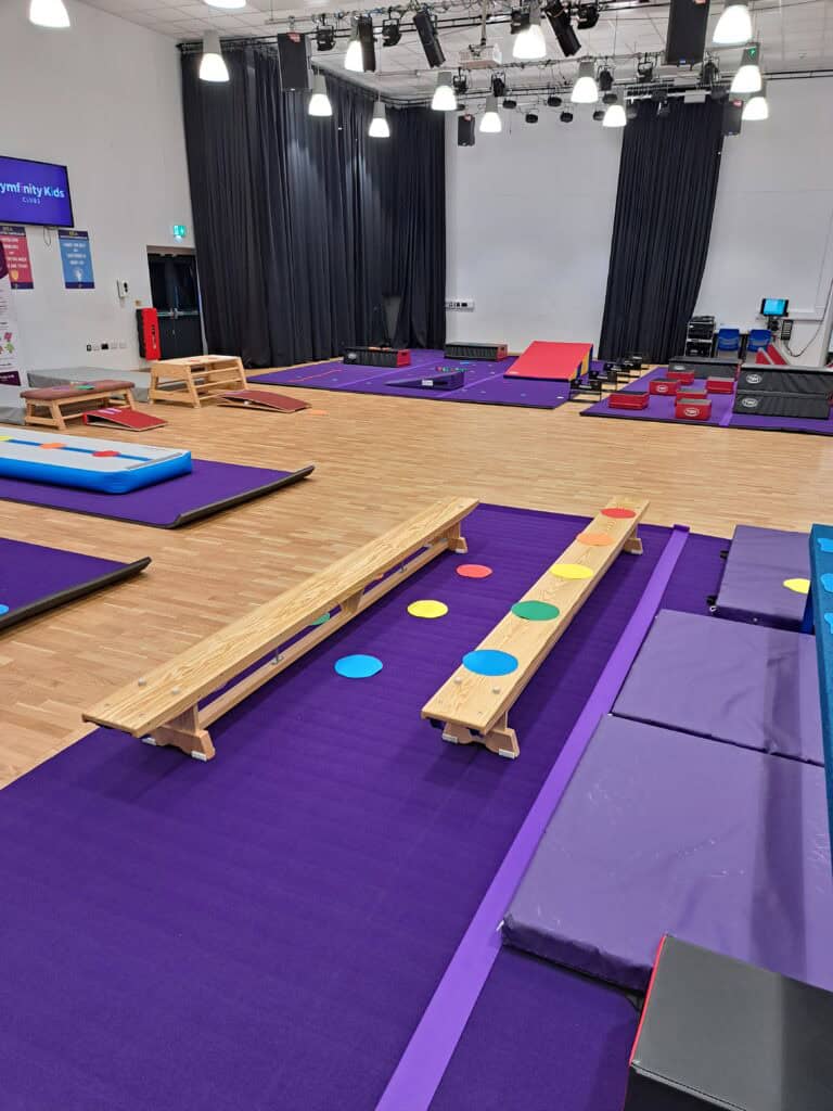 Brightly coloured sensory equipment and soft mats in a spacious indoor play area designed for children with special needs or sensory processing disorders. The room features various textures and height.
