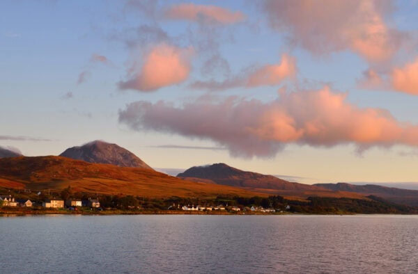Serene view of the Hebrides with mountain backdrop and calming waters; perfect for nature and travel lovers.