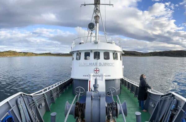 Ferry boat on water with offshore islands and cloudy sky, scenic Hebrides adventure.
