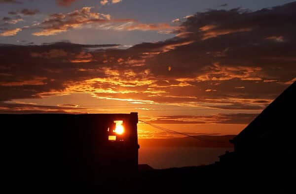 A stunning sunset captures the colourful sky and silhouette of island buildings in the Hebrides.