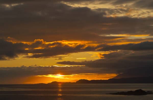 Stunning sunset in the Hebrides with colourful clouds and calm waters, ideal for island adventures and nature exploration.