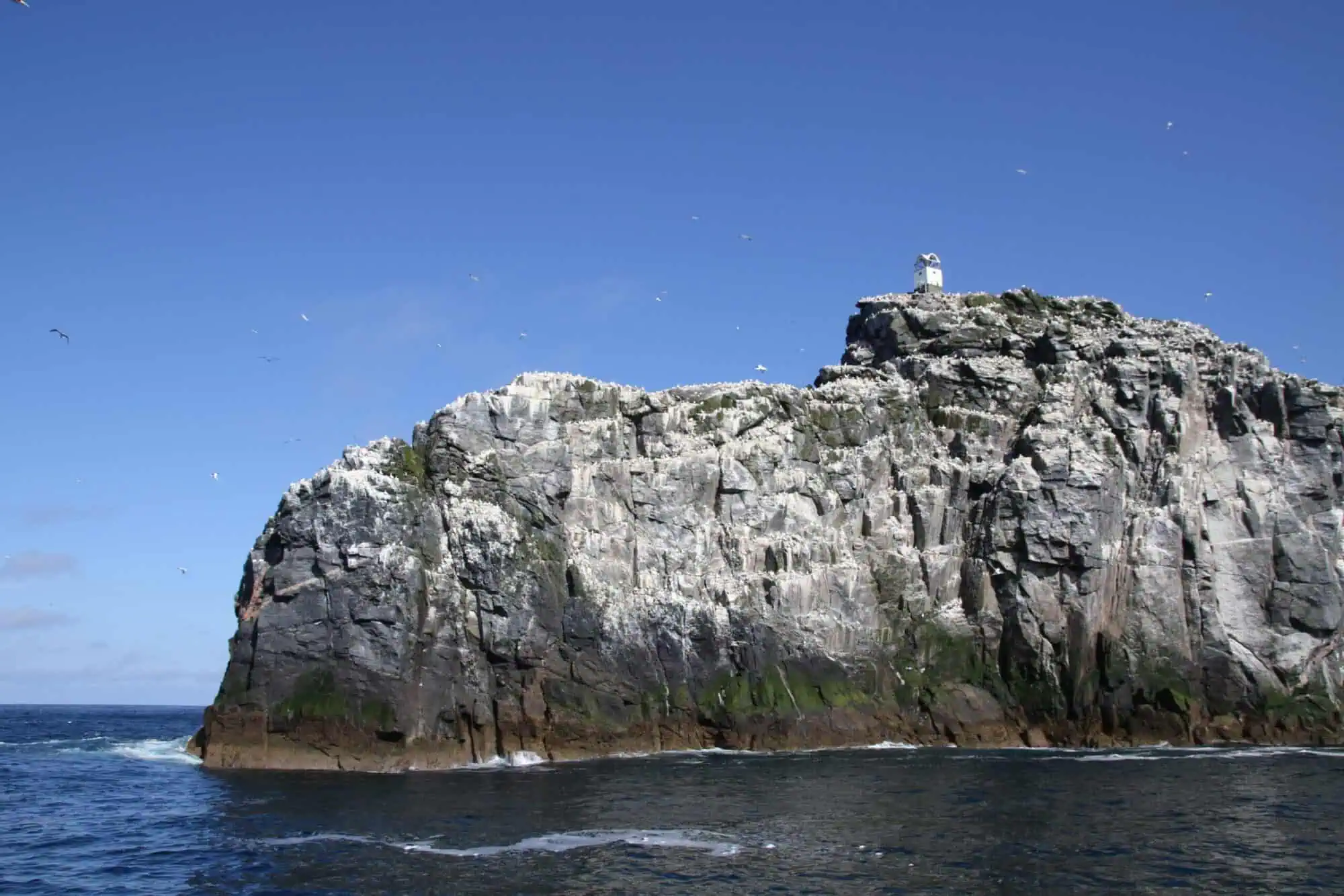 Seaside cliffs with lighthouse in Hebrides, home to seabirds and stunning ocean views. Perfect for adventure and nature lovers.