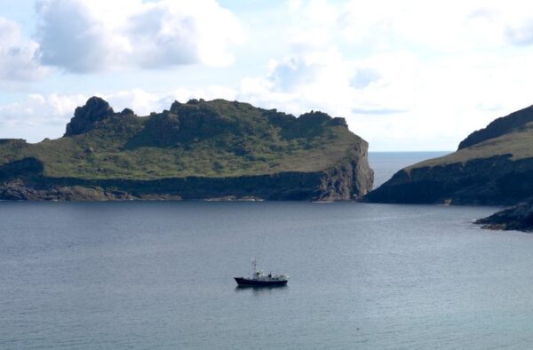 Scenic Hebridean waters featuring rugged islands and a lone boat, perfect for exploration and adventure.