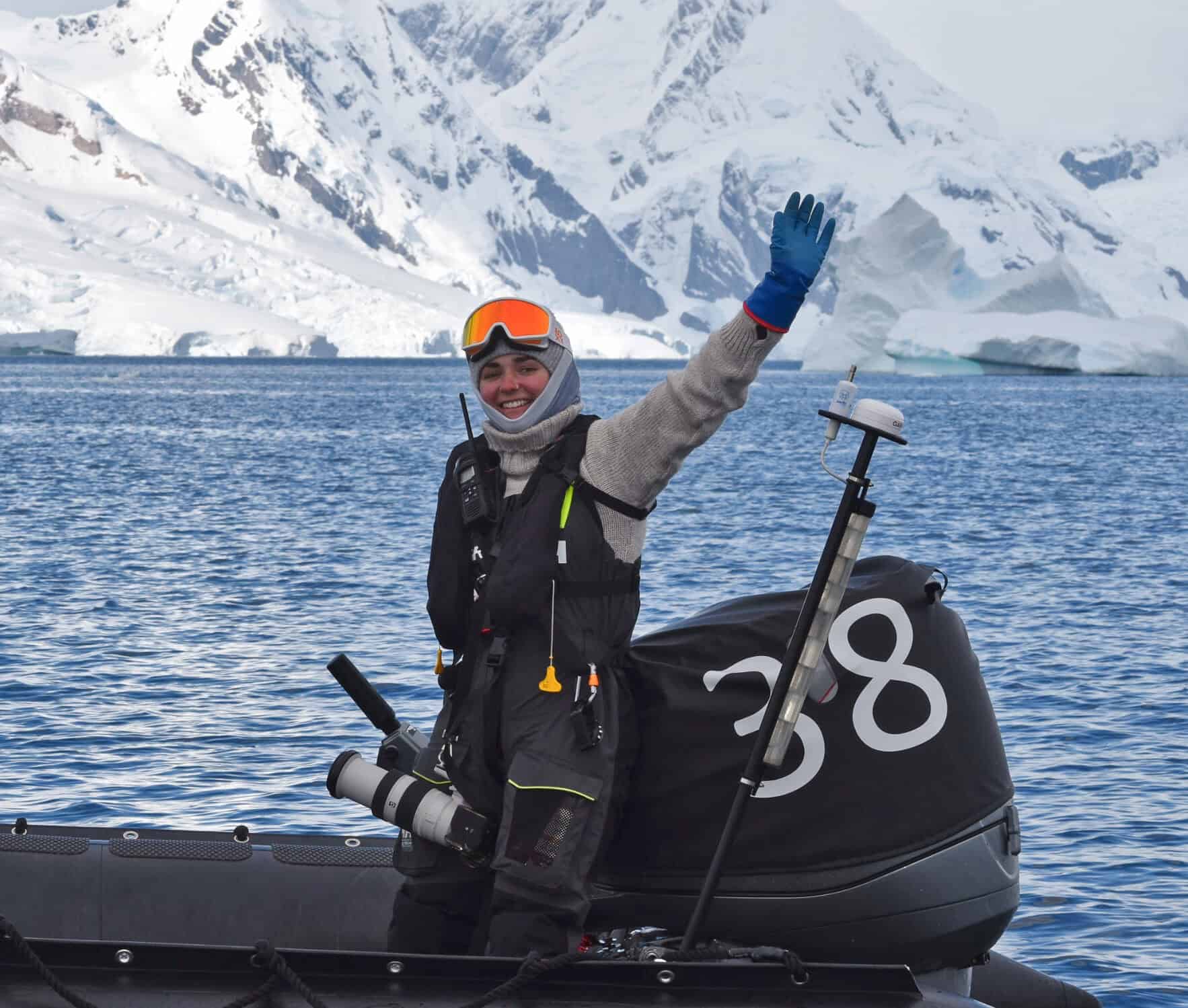 Young woman in waterproof gear on zodiac boat in icy Scottish waters, exploring Hebridean wilderness.