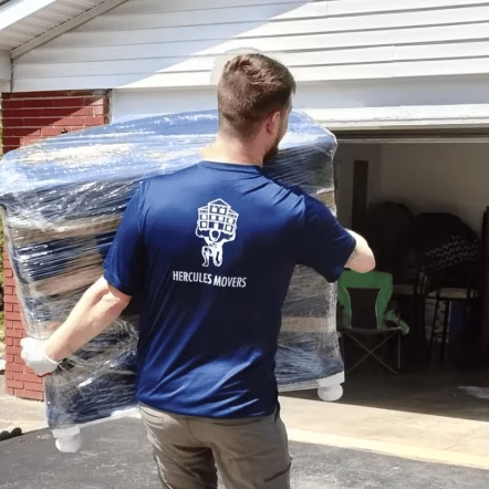 Mover carrying padded furniture into garage