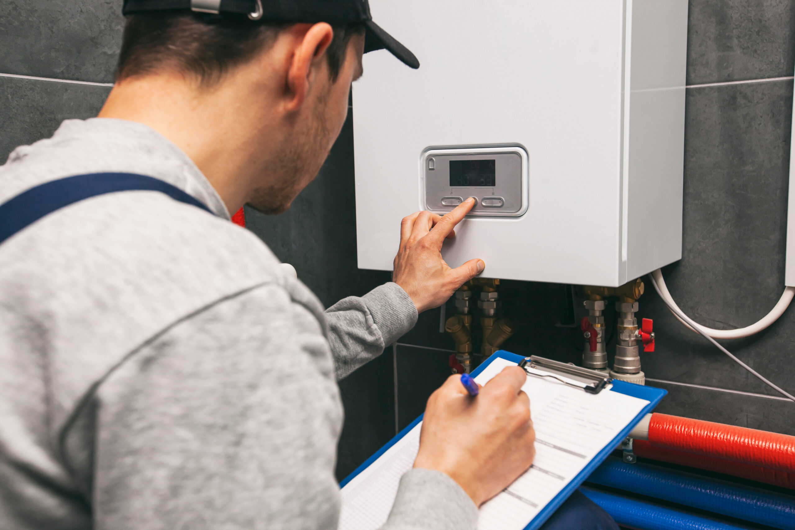 Gas boiler technician inspecting and adjusting a boiler system.