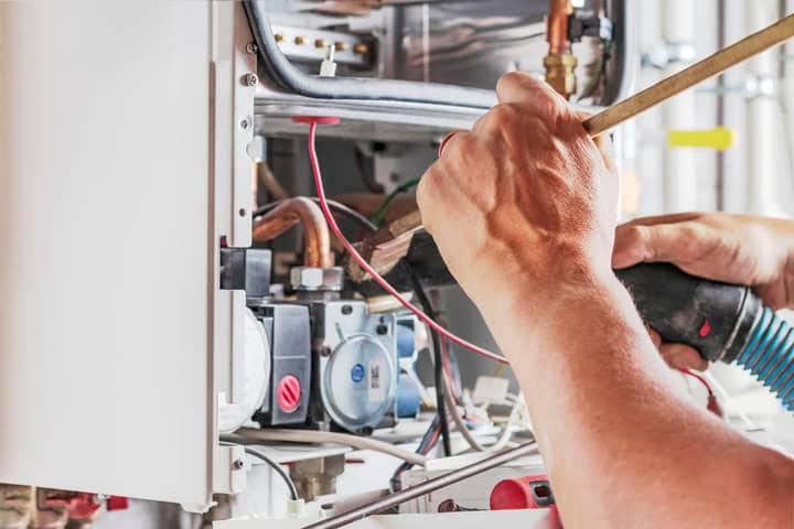 Gas technician repairing boiler with tools in Halesowen.
