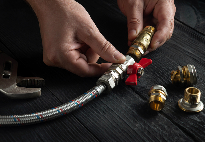 Technician connecting gas pipe fittings for heating system.