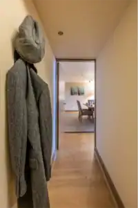 Entrance hallway with coat rack and hat, leading to living area.