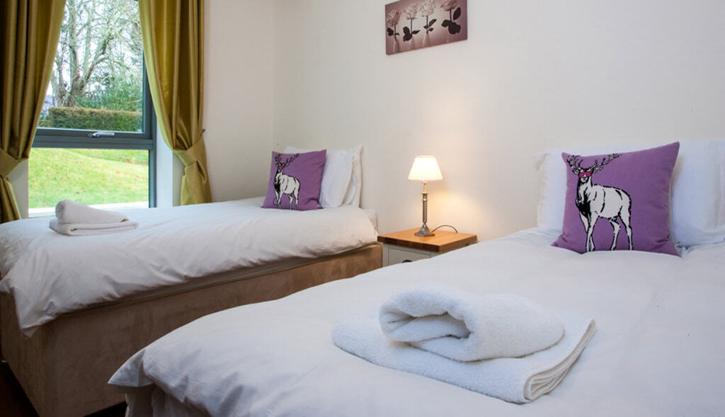 Comfortable Highland Club guest room with twin beds and scenic window view.