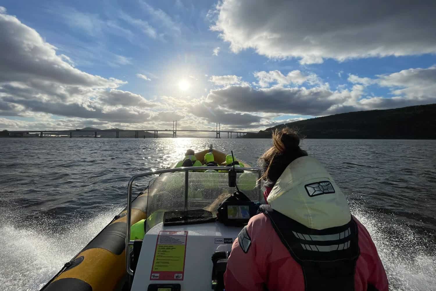 Boat tour on Loch Ness with scenic views and the bridge in the background.