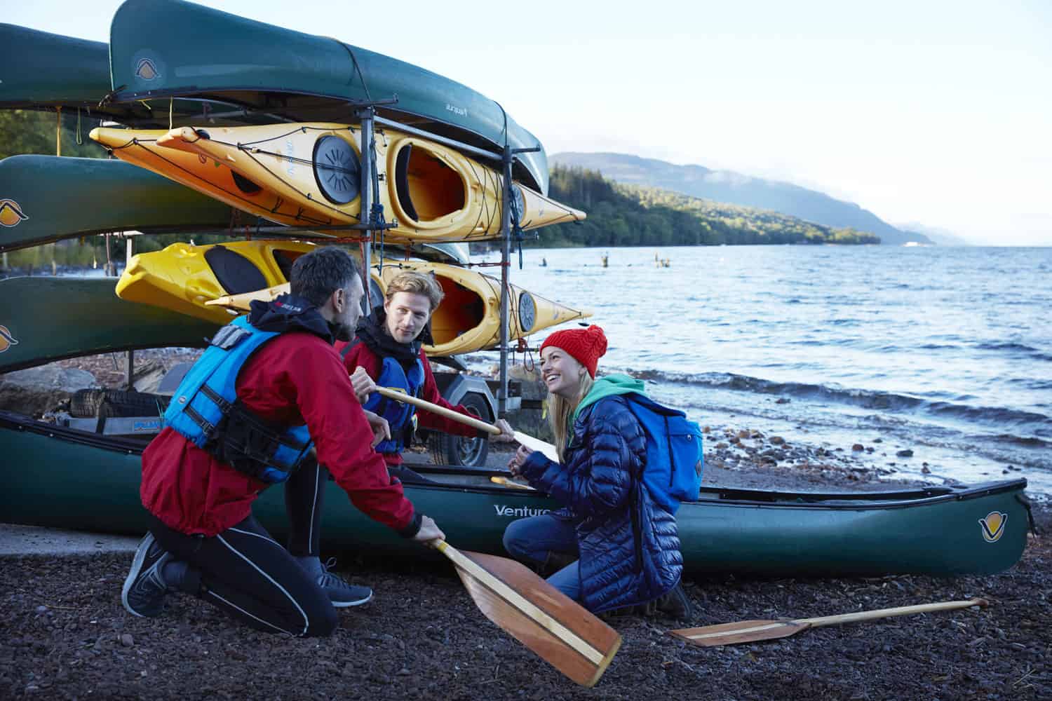 Group preparing kayaks on the shore at Highland Scotland for outdoor adventure.