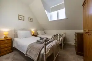Bright bedroom with twin beds, wooden furniture, and skylight in Highland Club Scotland property.
