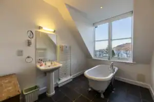 Bathroom with clawfoot bathtub and large window overlooking mountains in Highland Club Scotland.