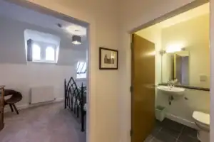Bright bedroom with sloped ceiling, double windows, and classic decor, adjacent to a modern en-suite.