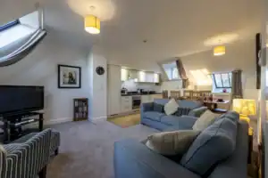 Bright, spacious living room with comfortable sofas, large windows, and cosy lighting.