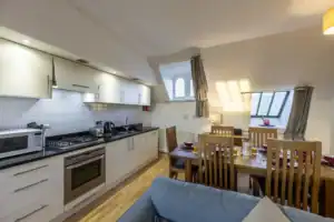 Bright kitchen with white cabinets, black countertops, and dining table with red tableware.