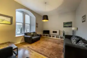 Spacious living room with large window, sofas, and modern fireplace at Highland Club Scotland.