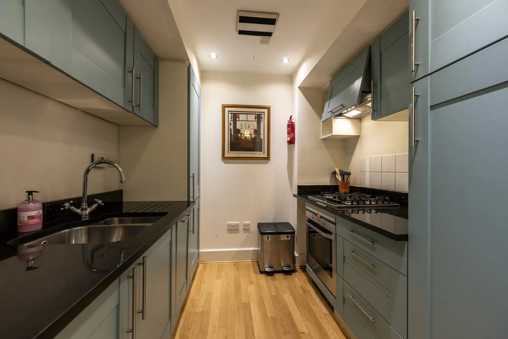Bright Highland Club kitchen with blue cabinets, black countertops, and wooden flooring.