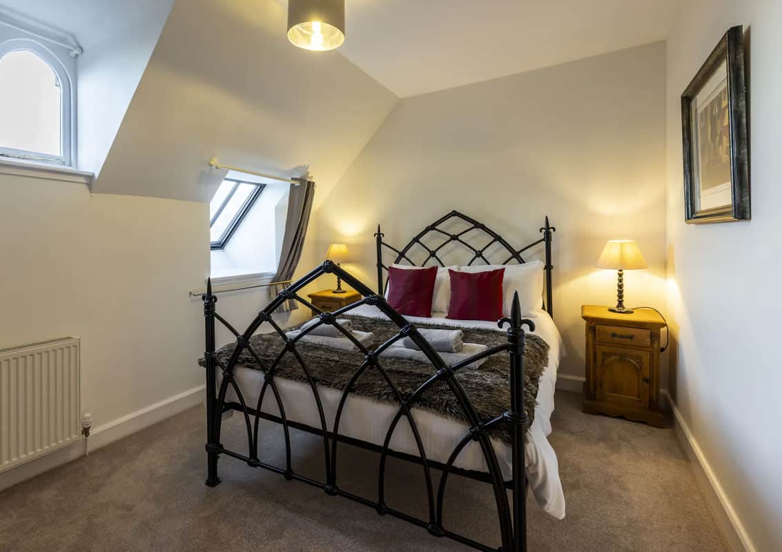 Charming bedroom with wrought iron bed and cosy lighting at Highland Club Scotland.