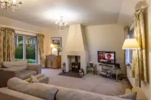 Comfortable living room with fireplace, TV, and large windows in Highland Club Scotland.
