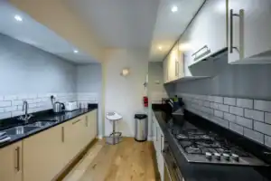 Modern kitchen with white cabinets, black countertops, and stainless steel appliances at Highland Cl.