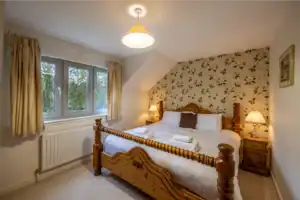 Highland Club Scotland bedroom with wooden bed and floral wallpaper.