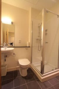 Suite bathroom featuring a glass shower enclosure, toilet, and sink in Highland Club Scotland accomm.