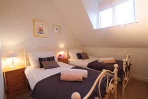 Comfortable bedroom with twin beds and soft lighting at Highland Club, Scotland.