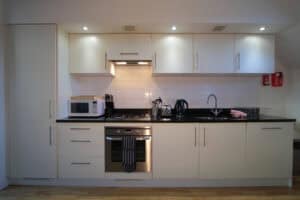 Modern kitchen with white cabinets and black countertops, featuring built-in appliances and sleek de.