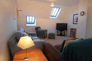 Comfortable Highland Club living room with sofas, TV, and skylights in a modern Scottish retreat.