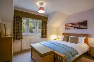 Comfortable bedroom at Highland Club with scenic window view and warm lighting.