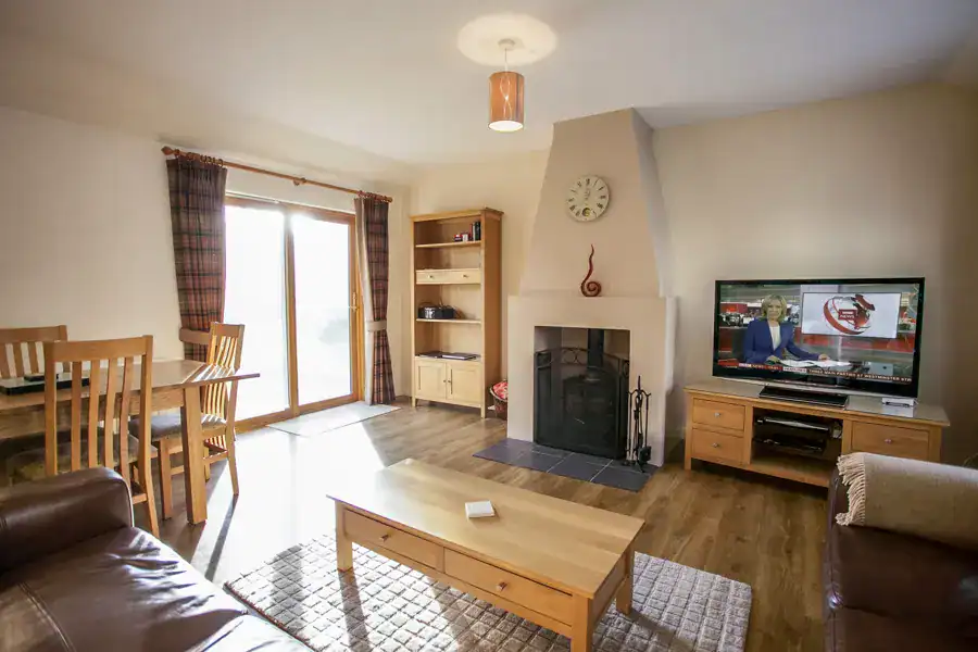 Bright living room with fireplace and TV at Highland Club Scotland.