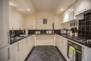 Highland Club Scotland kitchen with white cabinets and black countertops.