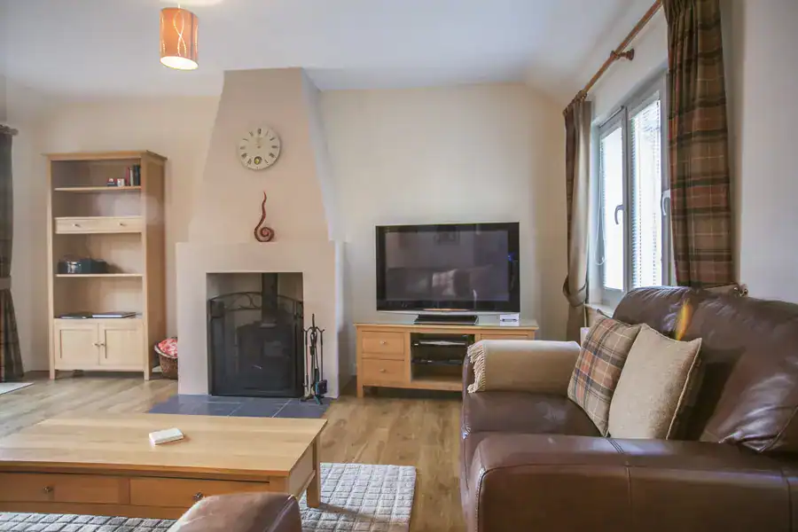 Comfortable Highland Club living room with fireplace and TV.