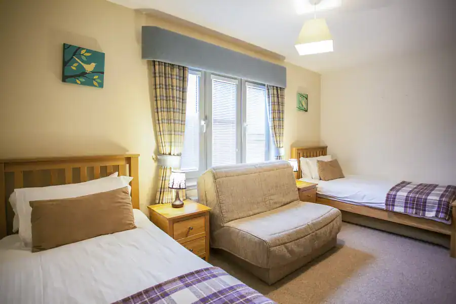 Bright Highland Club guest room with two single beds and a sofa.