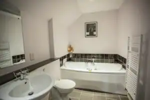 Contemporary bathroom featuring a bathtub, sink, and heated towel rail at Highland Club Scotland.