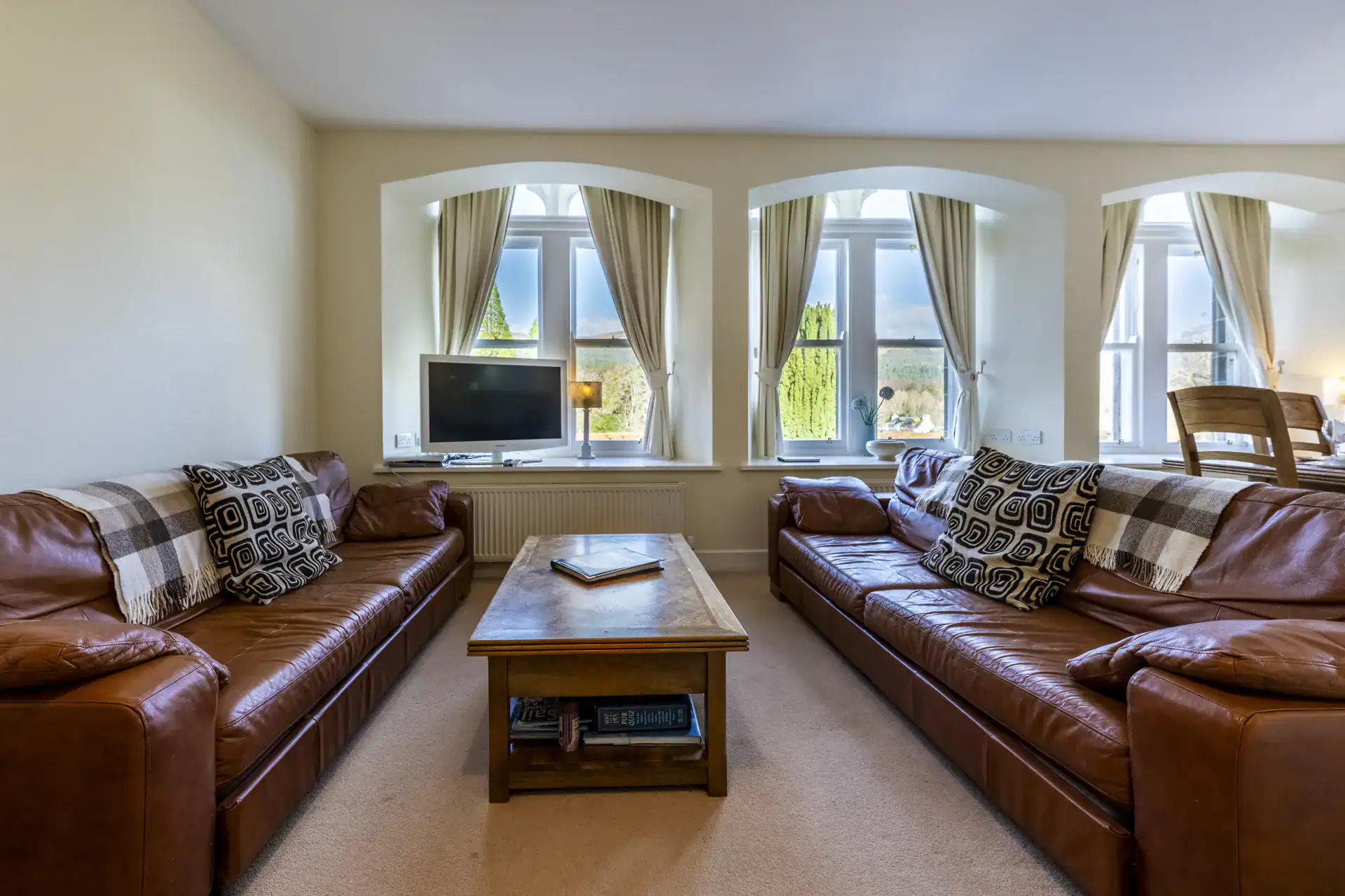 Bright living room with leather sofas and large windows in Highland Scotland.