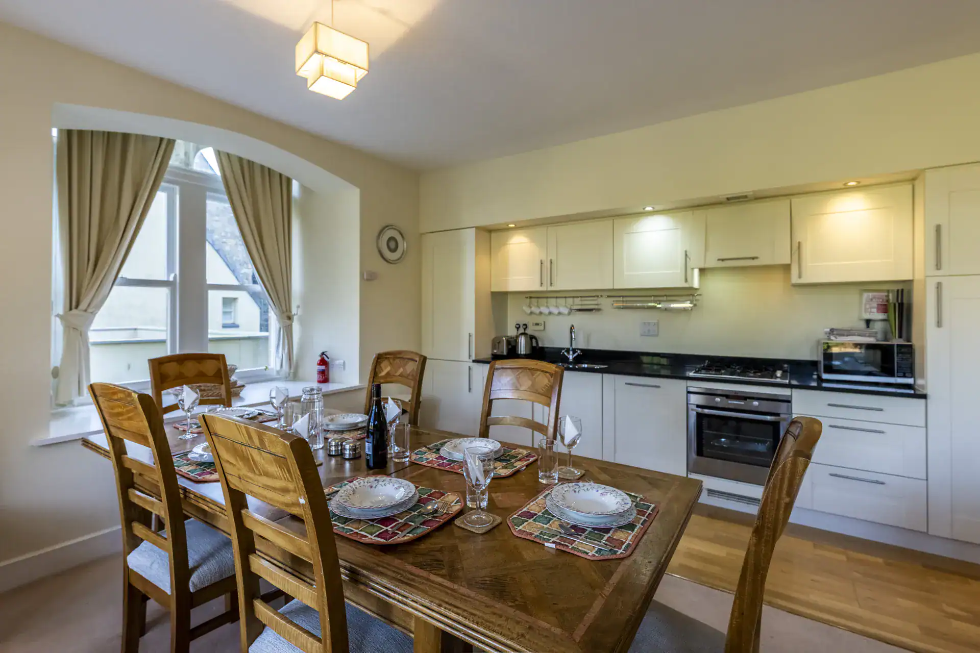 Bright kitchen with large window, cream curtains, and contemporary appliances.