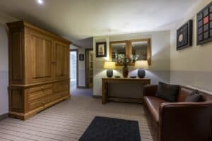 Highland Club Scotland lounge with wooden wardrobe, sofa, and wall art, showcasing elegant interior.