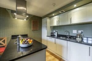Highland Club Scotland kitchen with white cabinets and black countertops.