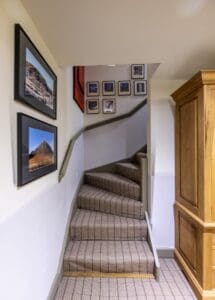 Interior view of a staircase at Highland Club Scotland, showcasing framed photos and wooden accents.
