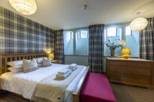 Comfortable Highland Club bedroom with tartan decor and natural light.