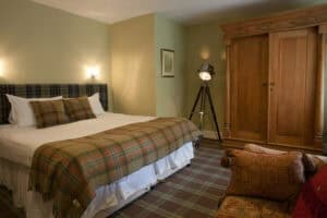 Comfortable bedroom at Highland Club with Scottish tartan decor and classic furnishings.