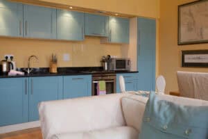 Kitchen with blue cabinets, black countertops, and modern appliances in Highland Club Scotland.