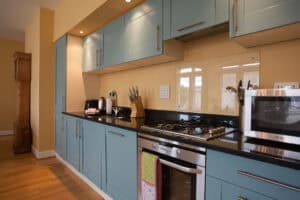 Modern blue kitchen with appliances, black countertop, and wooden flooring at Highland Club Scotland.